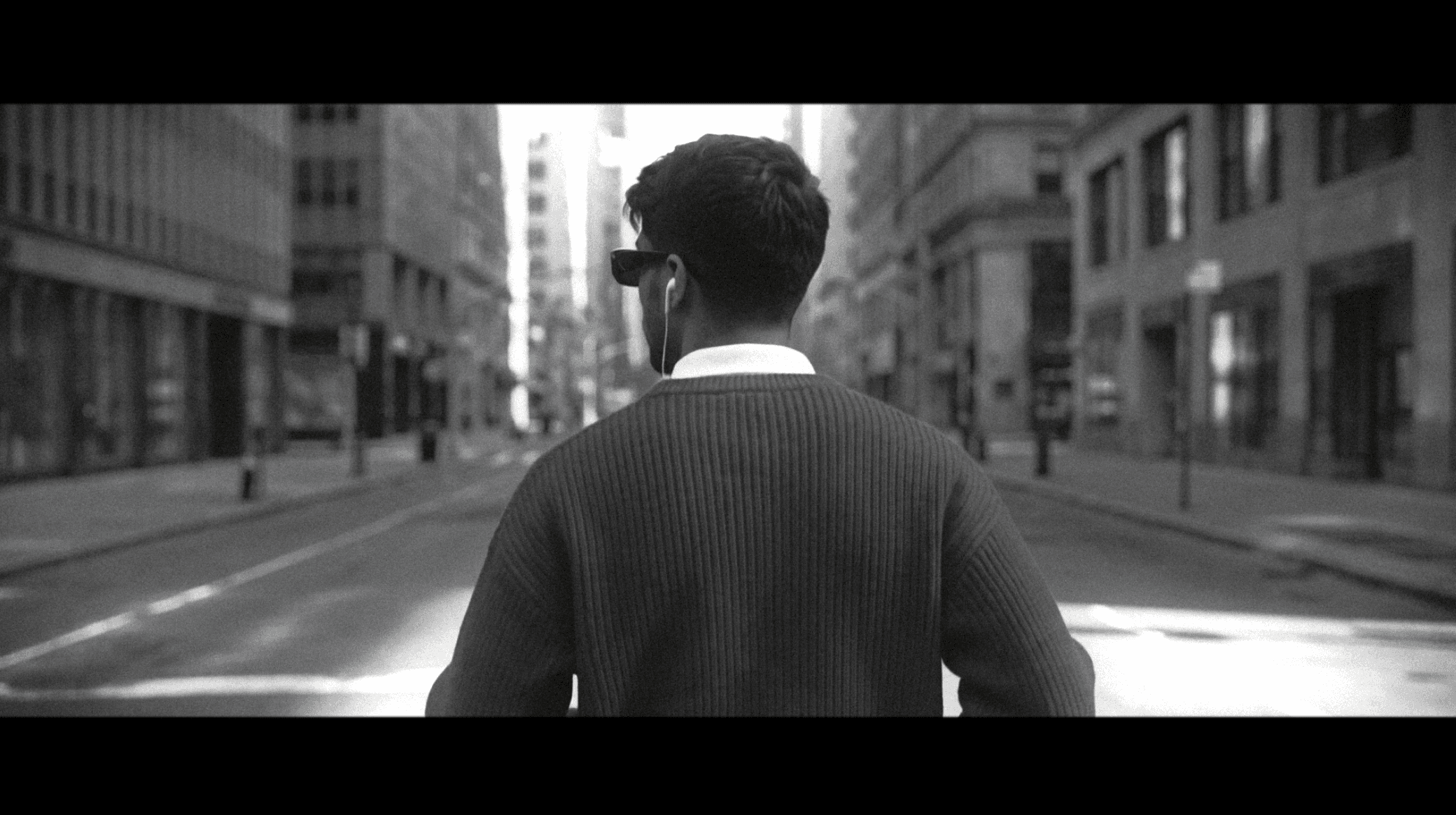 Graded still: the character walking away down an empty downtown street, shot from behind